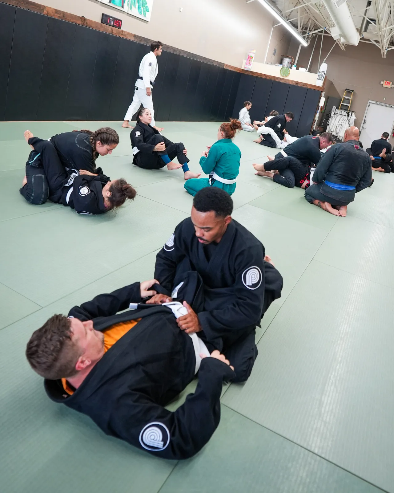 Adult students rolling together on the mats at Praxis Jiu Jitsu