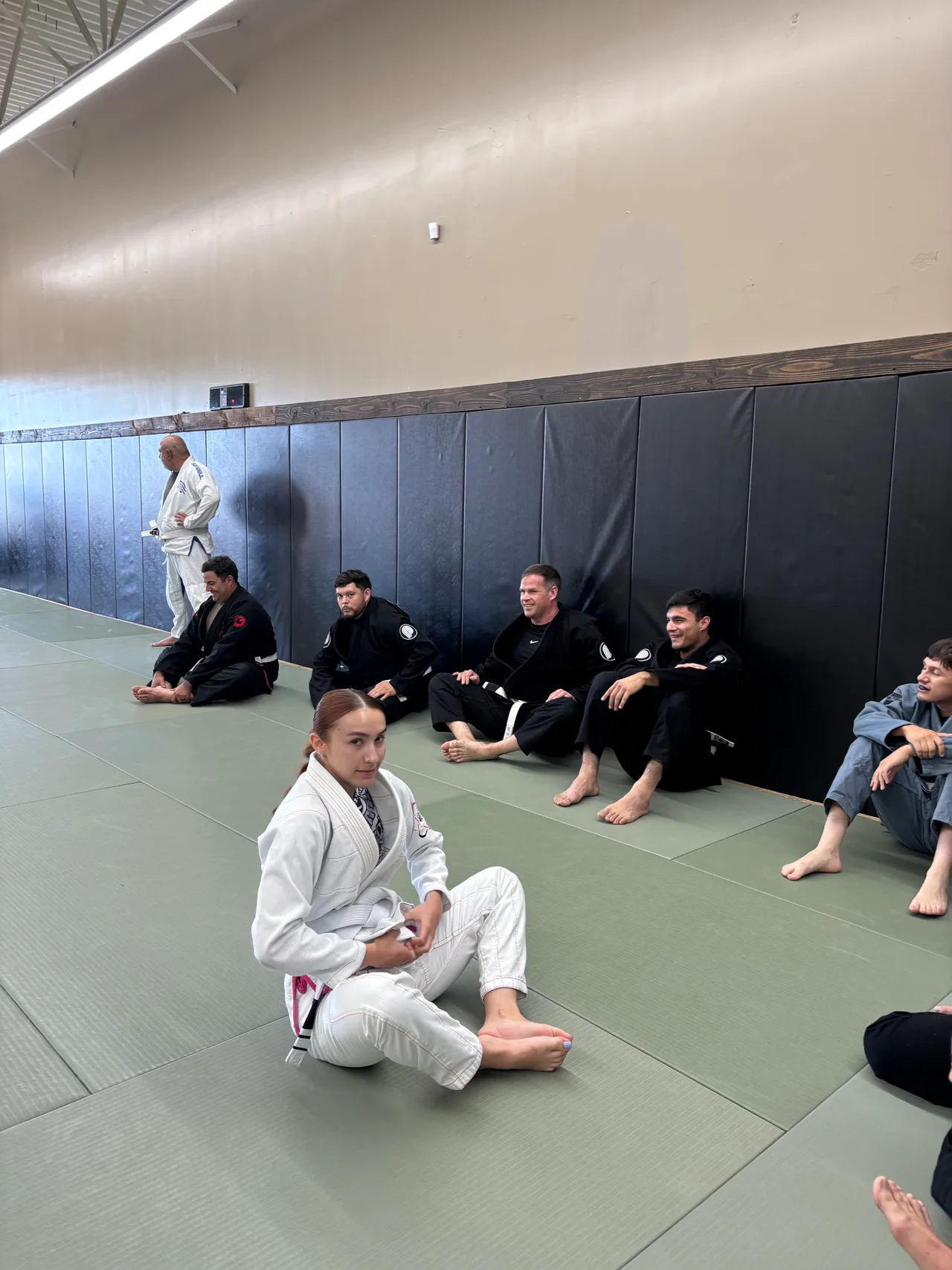 A white-gi instructor demonstrating a position as students watch