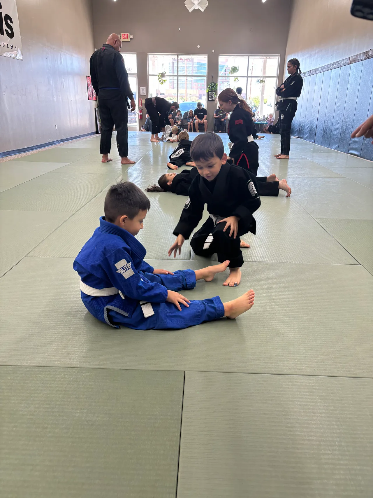 Two young students practicing a ground position in blue and black gis