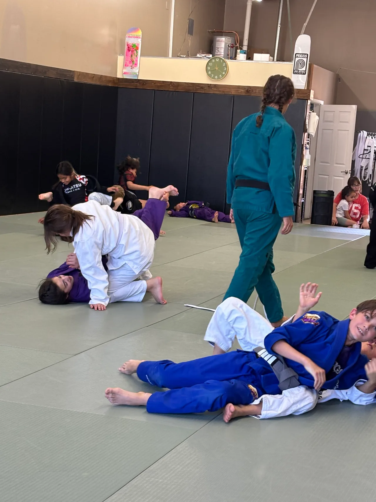 Young students practicing on the mats with a coach supervising