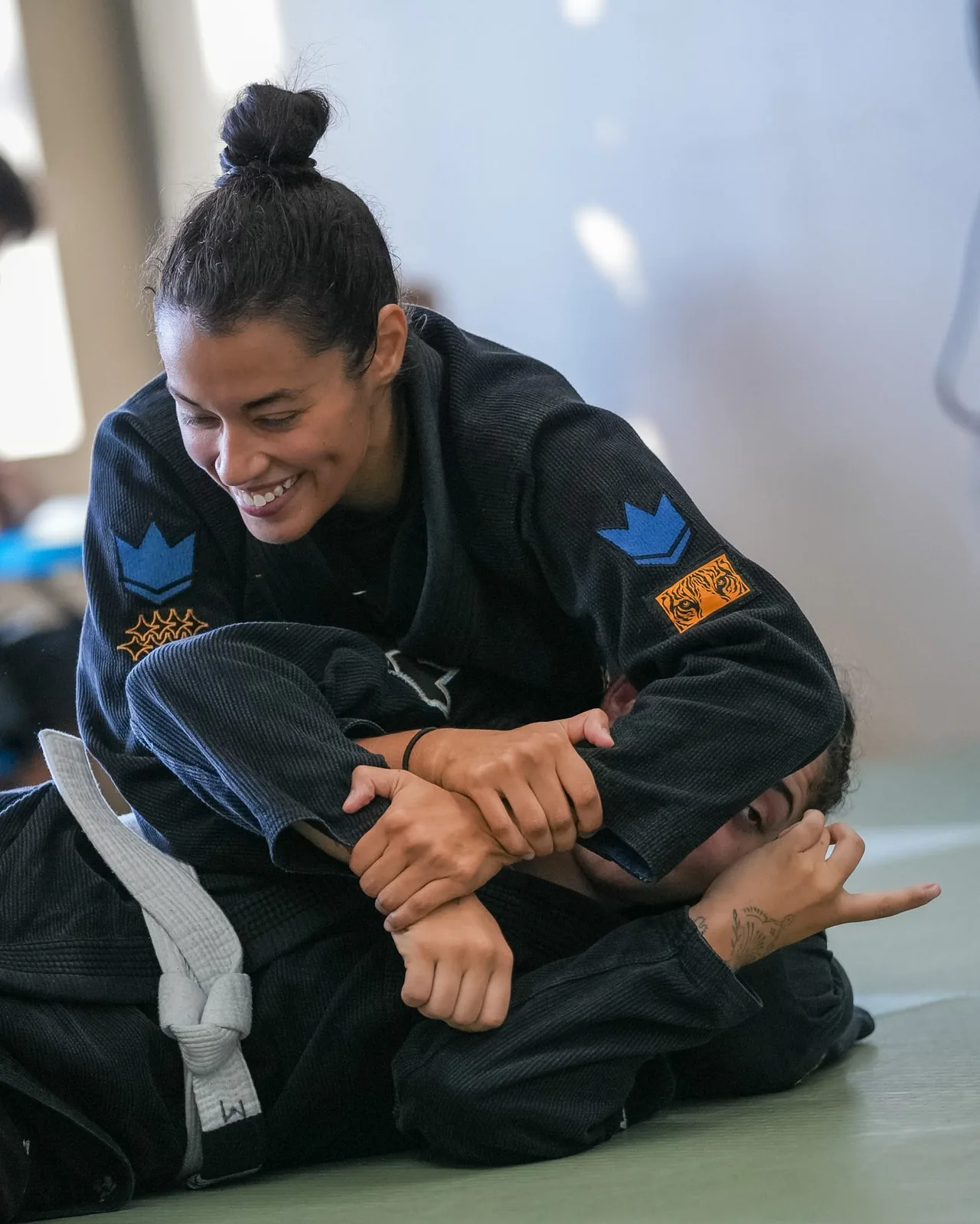 A woman practicing arm control with a training partner in Gi class